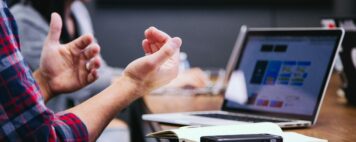 person talking with their hands to a group, all seated together at a table
