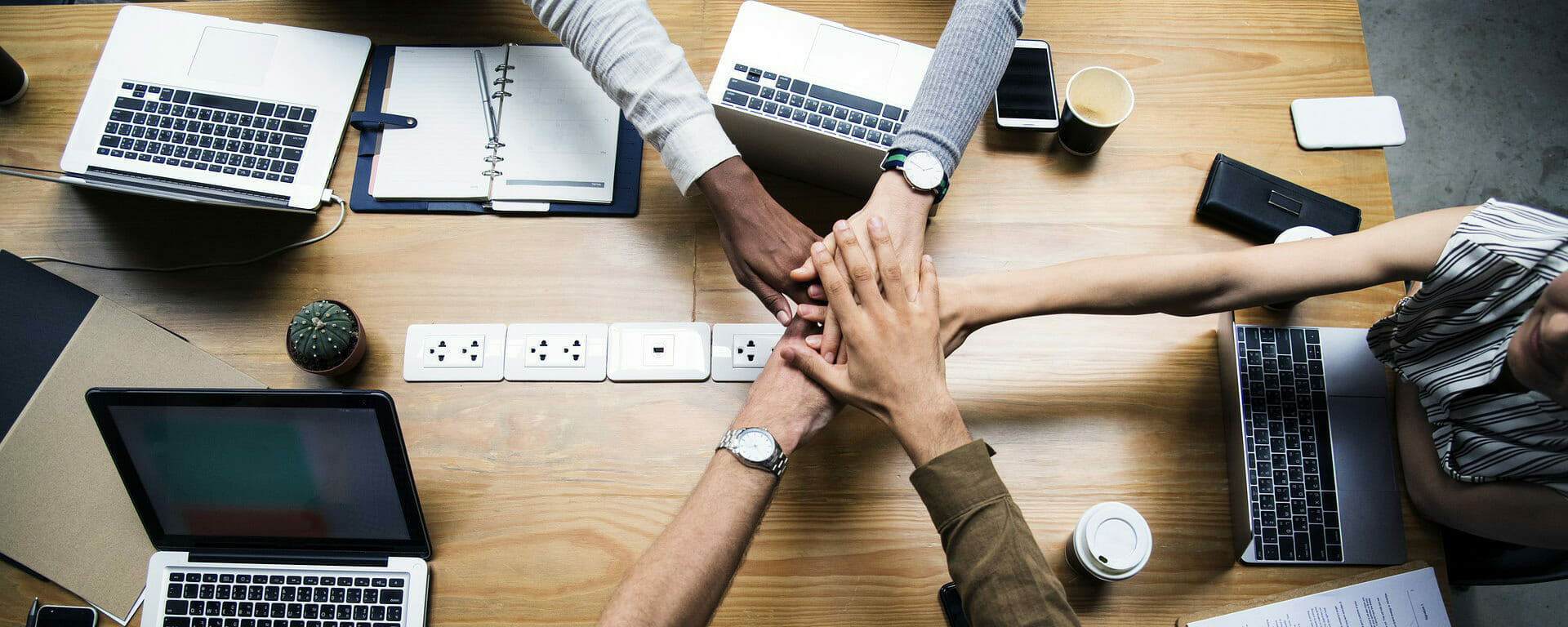 a diverse team with their hands on top of each other to suggest teamwork