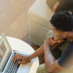 young male student using his laptop in a campus learning space.