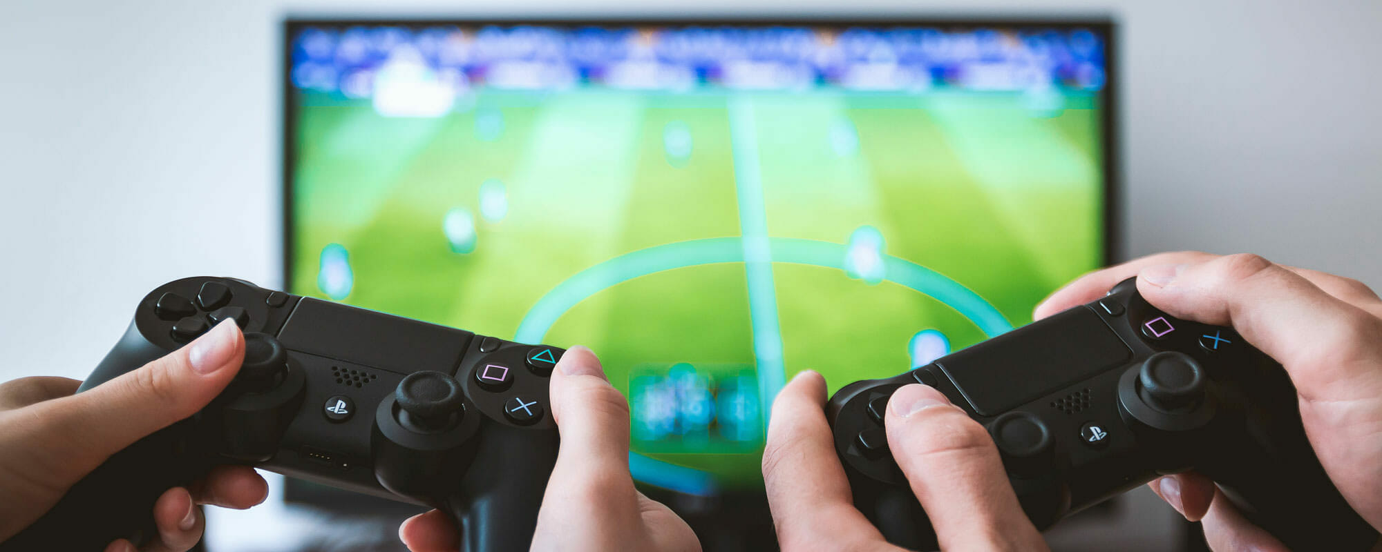 two people holding up play station controllers with the video game screen behind