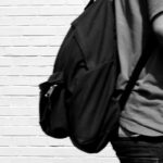 black and white image of a student walking by a brick building