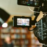 video camera with a student in front of books