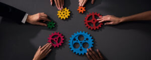 diverse group of individuals pushing colorful gears on a table to each other