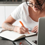 Woman taking notes while on laptop