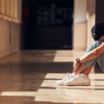 Sad young student sitting in the hall.