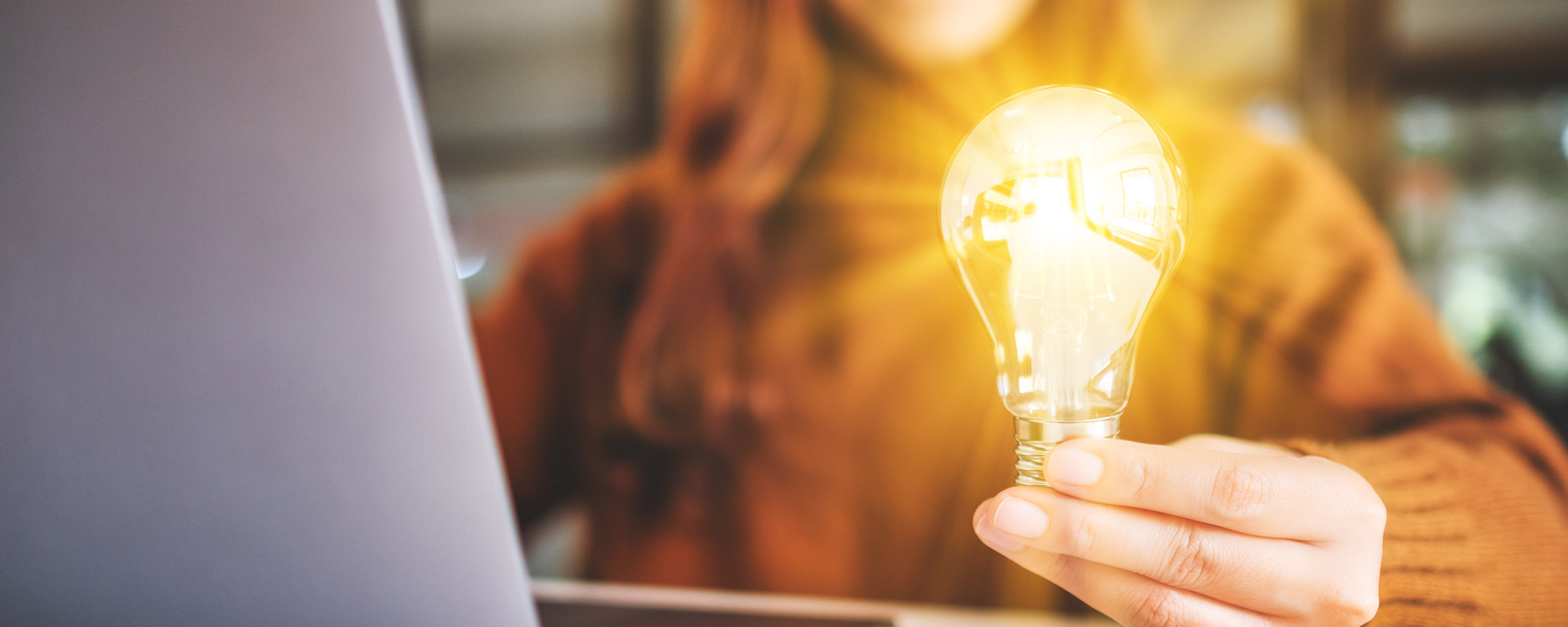 Person learning online and holding a light bulb