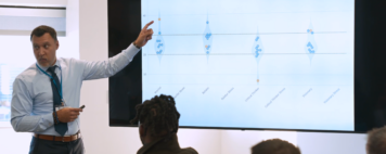 Image shows an Academic Impressions Workshop where a presenter is pointing to a power point that is displaying a team's Five Paths to Leadership® assessment scores under normal circumstances.